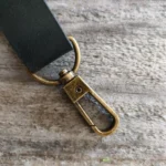 nahkainen avaimenperä, jossa mustaa nahkaa ja kapea antiikkimessinkinen lukko